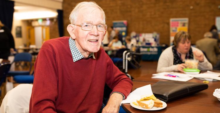 Man sitting at a table with a slice of cake smiling at the camera