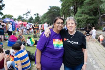 Two women at a pride march with their arms round each other