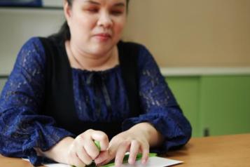 visually impaired lady reading braille at a table 