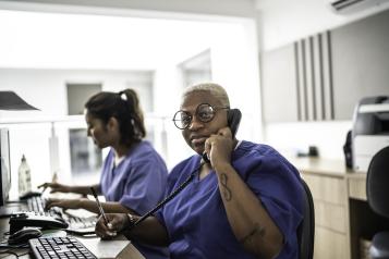 Receptionist staff at computer taking a telephone call