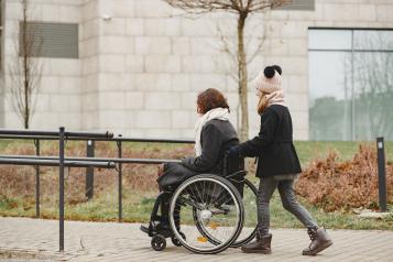 Female in wheelchair being pushed by carer outside