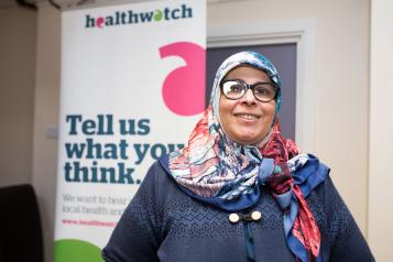 Volunteer standing in front of a Healthwatch banner